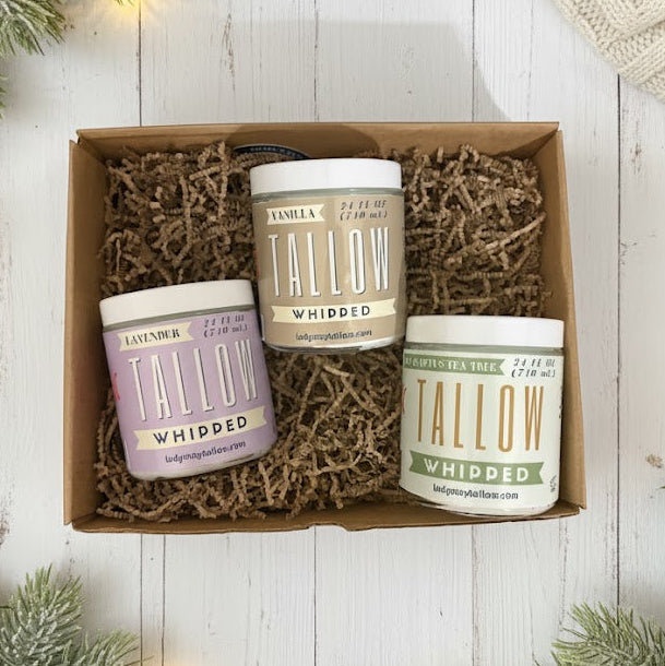 Three candles in a box with Christmas decorations on a wooden surface